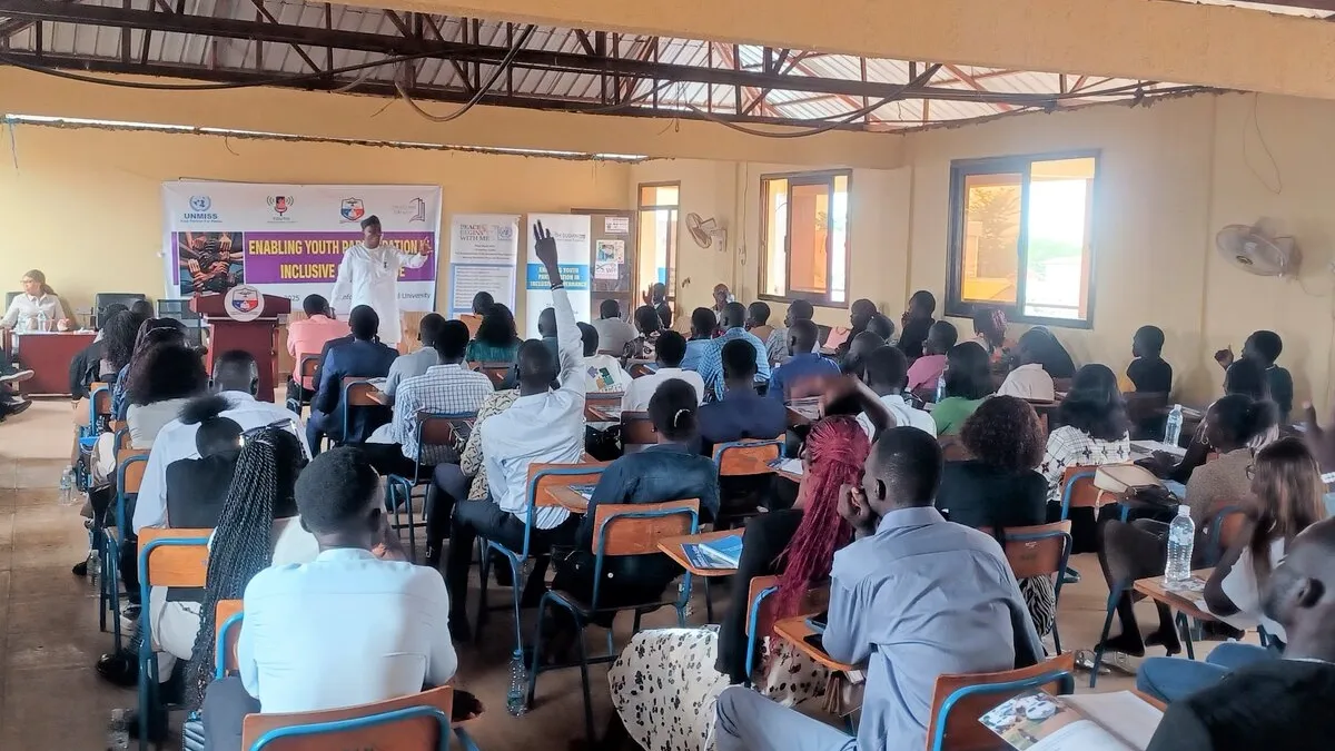 A series of ongoing lectures are bringing young students from South Sudan together to discuss their vital role in shaping public opinion and encouraging momentum in the country’s efforts to transition into a true democracy. A classroom-style setting with many people seated at desks facing a speaker at the front, where banners and a presentation on youth empowerment are displayed.
