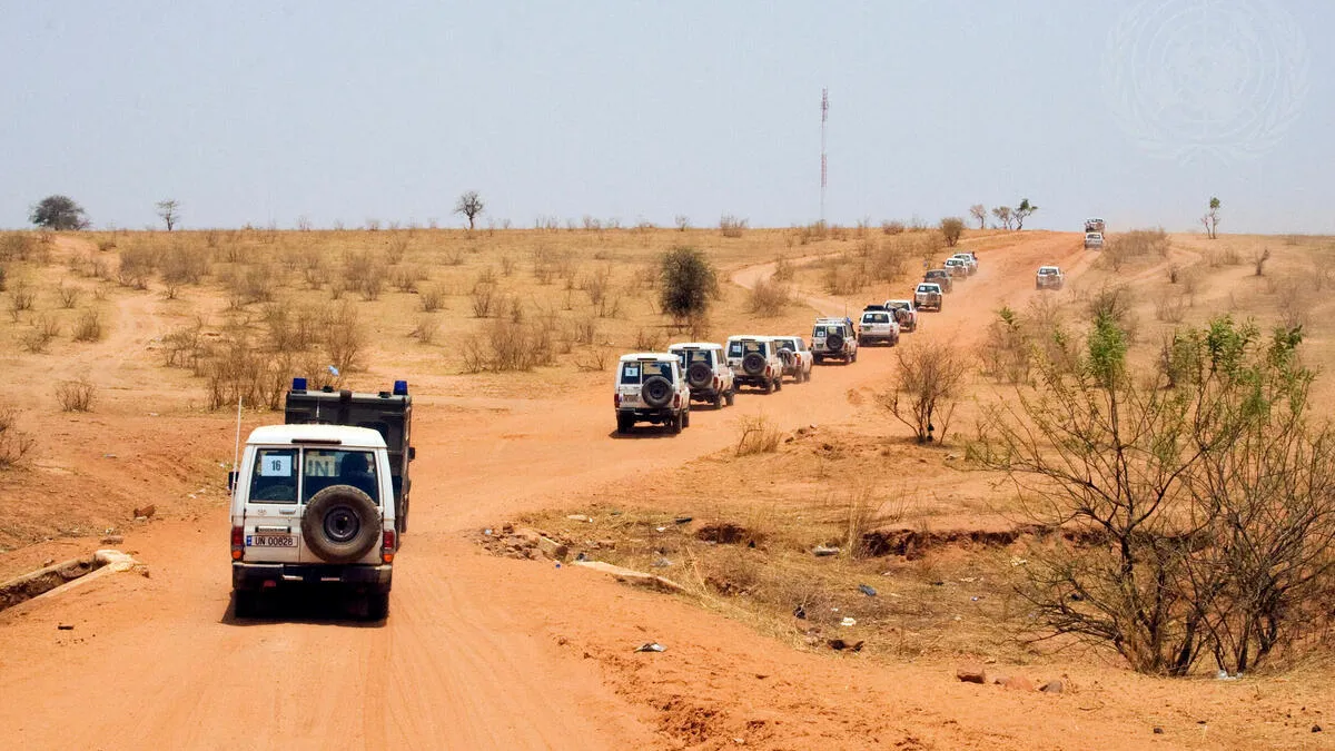 A United Nations convoy escorts an African Union delegation of former Presidents of African countries on their way to visit the Djabal Refugee Camp. A convoy of UN four wheel drive vehicles along a red dirt road.