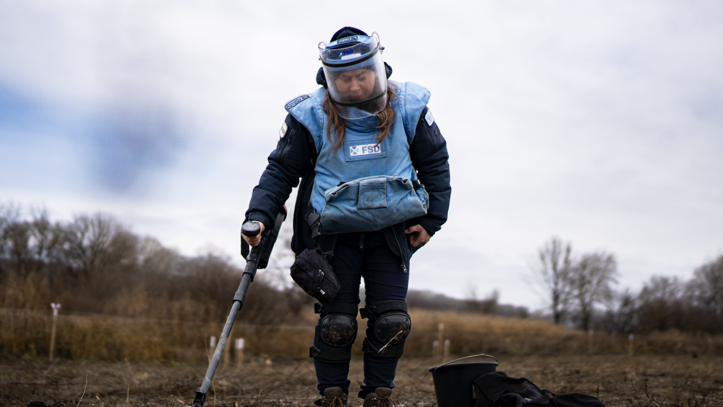 a female deminer is working in a field