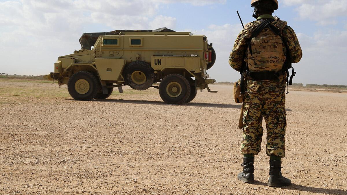 a millitary man is standing in front of a military truck