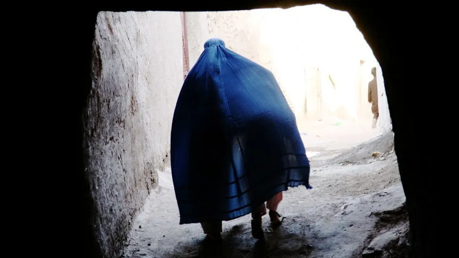An Afghan woman covers a child under her Borqa while passing through a tunnel in Herat, Afghanistan.