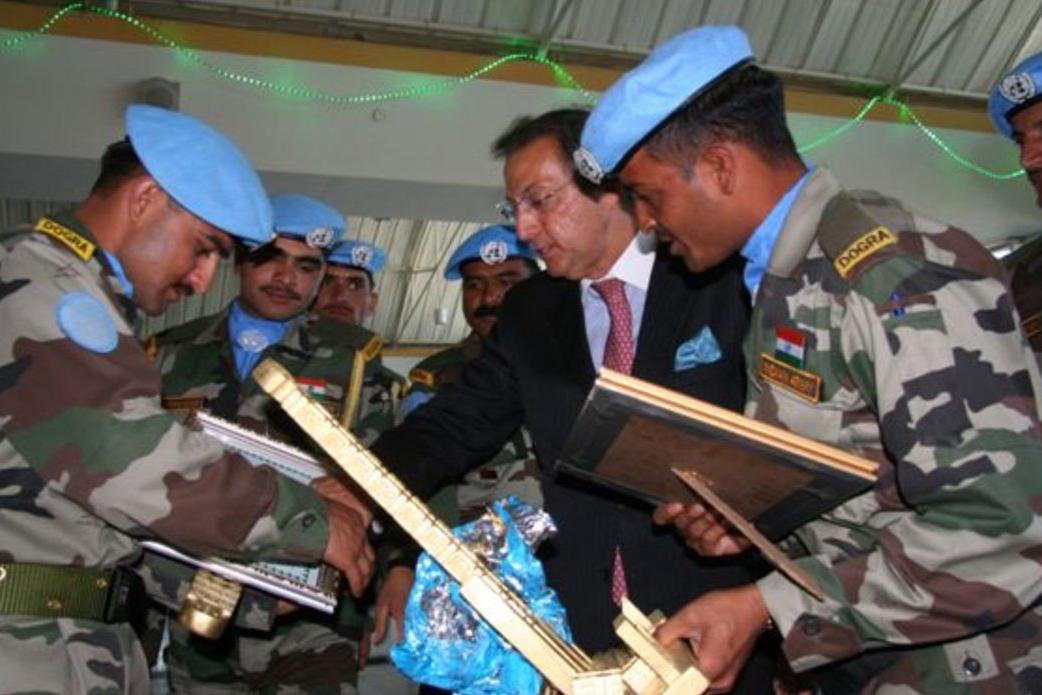 Peacekeepers in blue berrets shake hands at a farewell ceremony
