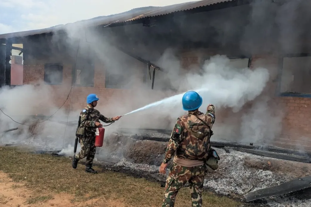 Deux casques bleus éteignent un incendie dans un bâtiment.