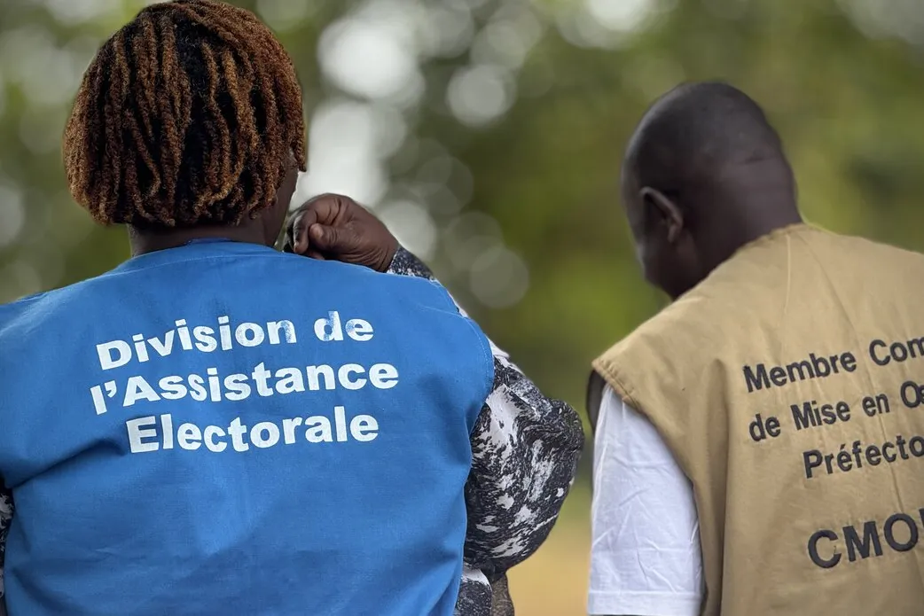 Un représentant porte une veste avec les mots « Division de l’Assistance Électorale ».
