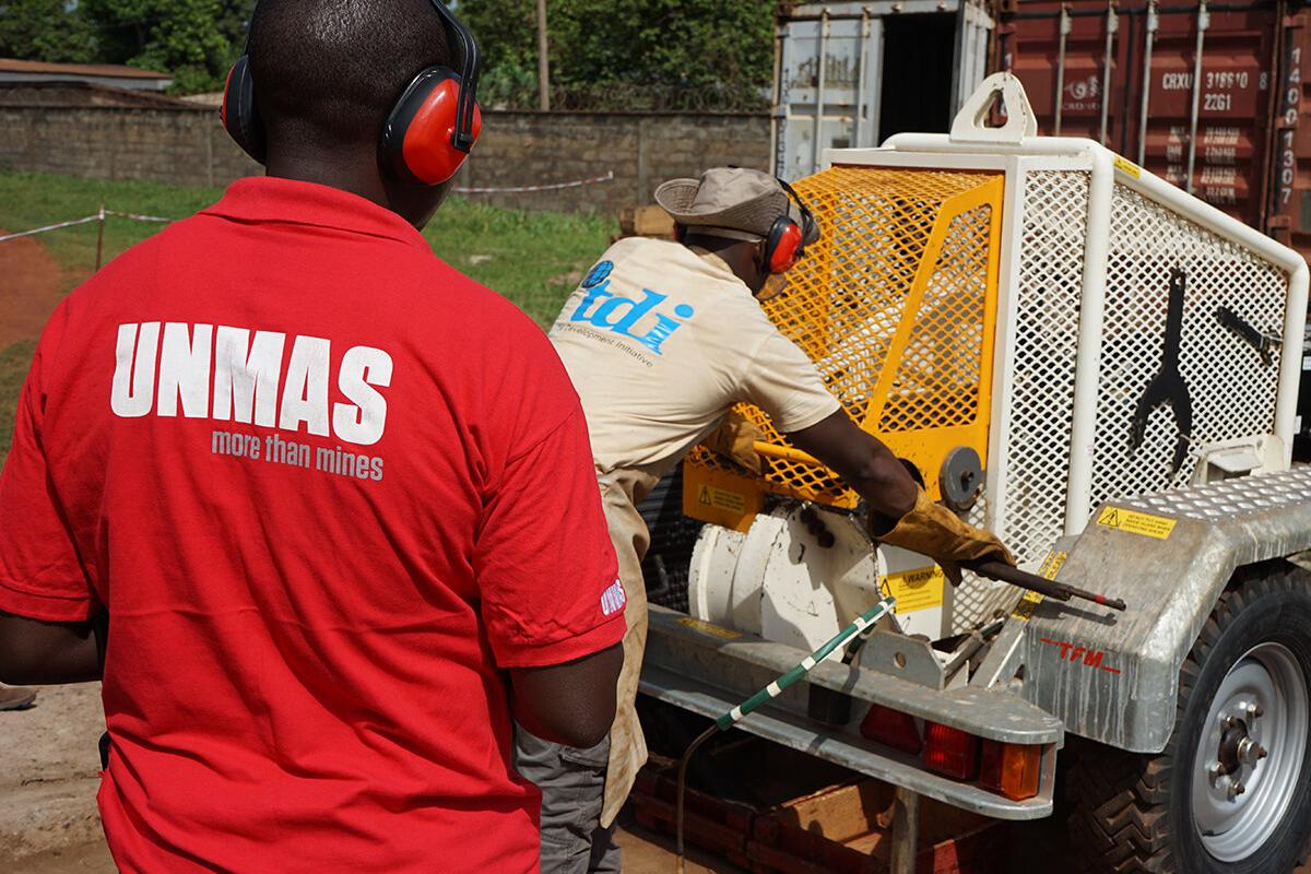a men with a red T-shirt is standing behind a man conducting weapon destruction