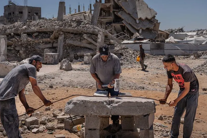 Three men begin the process of rebuilding their lives amidst the rubble of destroyed buildings in Jabalia, Gaza.