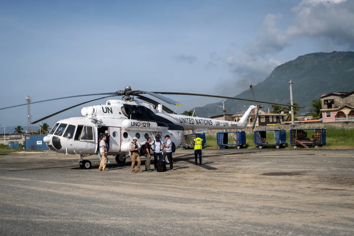 A United Nations helicopter on the ground in Cap-Haïtien, Haiti, with personnel gathered beside the aircraft