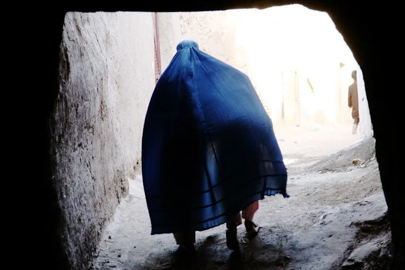 An Afghan woman covers a child under her Borqa while passing through a tunnel in Herat, Afghanistan.