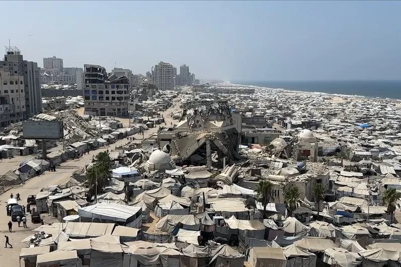 Massive tent settlement of displaced residents extends along the damaged Gaza coastline.