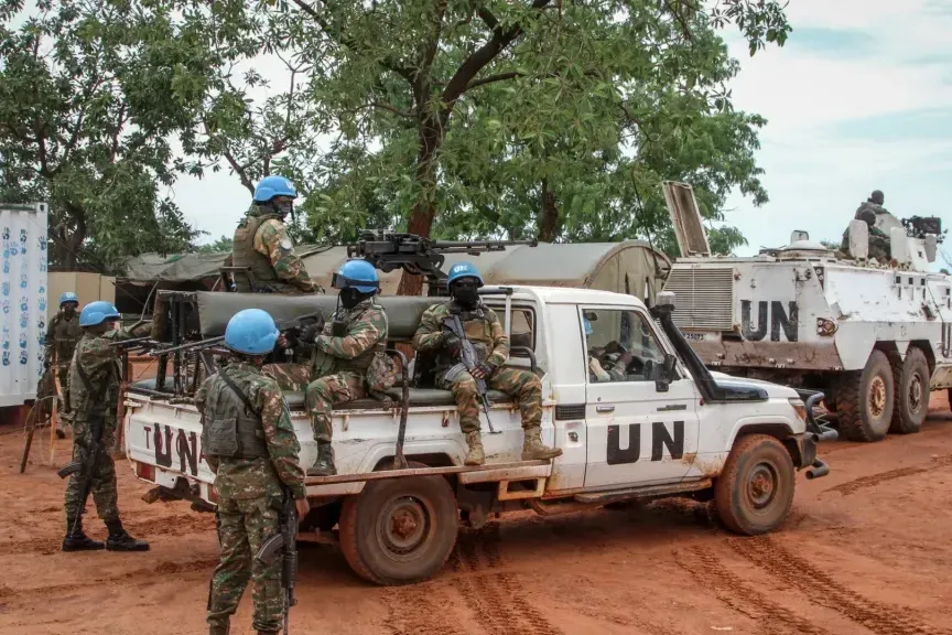 Peacekeepers are seated on a UN vehicle.