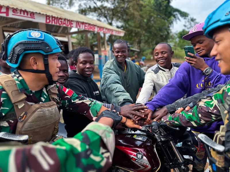 Peacekeepers join hands with young people.