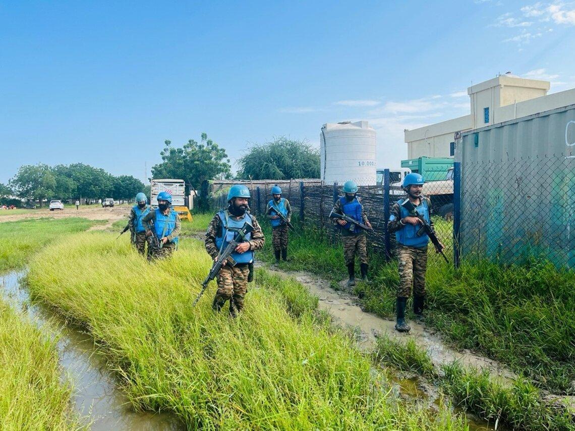 Armed peacekeepers stand on patrol outside industrial-looking buildings
